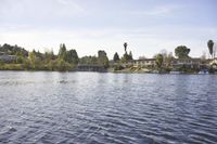 an empty lake surrounded by many buildings and boats in the water with mountain in the background