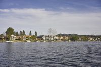 an empty lake surrounded by many buildings and boats in the water with mountain in the background