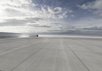 an air plane on the tarmac with a cloudy sky in the background in this image