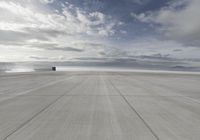 an air plane on the tarmac with a cloudy sky in the background in this image