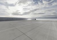 an air plane on the tarmac with a cloudy sky in the background in this image