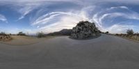 this is a fish eye lens photo taken on the side of a road with a very large rock on one side,