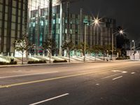 a empty street has several lights along side of it at night with the city light behind them