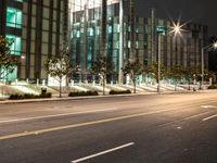 a empty street has several lights along side of it at night with the city light behind them