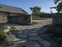 a home with stone stepping around the front yard and the large door leading to the front yard