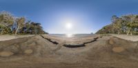 a fish eye lens on a beach with a view of the water, and some boats