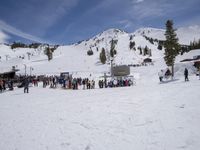 the group of people are on the slope outside of the lodge on the mountain with skis and snowboards