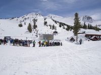 the group of people are on the slope outside of the lodge on the mountain with skis and snowboards