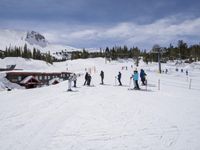 the group of people are on the slope outside of the lodge on the mountain with skis and snowboards
