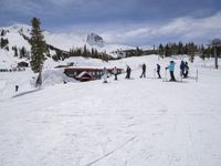 the group of people are on the slope outside of the lodge on the mountain with skis and snowboards