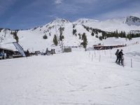 the group of people are on the slope outside of the lodge on the mountain with skis and snowboards