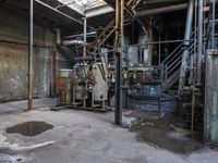 a fire hydrant in an old industrial setting in a factory building, with a lot of equipment, exposed ceilings and a cement floor