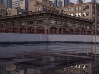 a large building with a reflection on the pavement in the street behind it, a reflection of the building