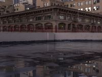 a large building with a reflection on the pavement in the street behind it, a reflection of the building