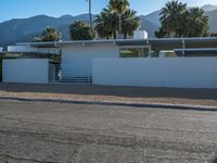 a car is parked in front of a modern building with mountains in the background on a clear day