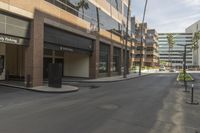 a empty street that has buildings on it in a big city with palm trees along the sidewalk