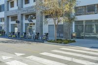 the bikes are parked on the side of the street as people walk by them at a crosswalk