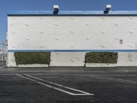 a white building with a blue roof and parking lot in front of it is no image here