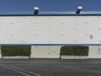 a white building with a blue roof and parking lot in front of it is no image here