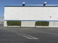 a white building with a blue roof and parking lot in front of it is no image here