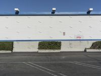 a white building with a blue roof and parking lot in front of it is no image here