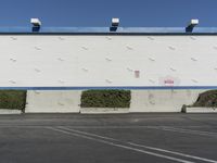 a white building with a blue roof and parking lot in front of it is no image here