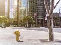 a yellow fire hydrant sitting in the middle of a city street with a flag on the pole