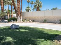 a stone that looks like a rock sits by the curb of a driveway in palm springs