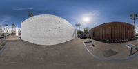 the sun rises over an empty parking lot with palm trees and a giant ball of cement