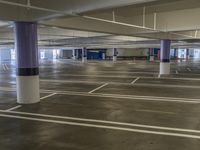 a empty parking garage with rows of parking spaces painted purple and white lines are visible