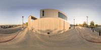 the skate park is very wide with cars parked around it and on its side, there is a ramp