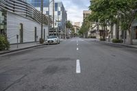 an empty street with white lines painted on it in the middle of town in a city