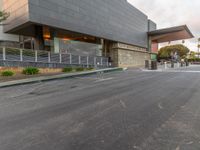 a grey fire hydrant stands on an empty street in front of a building with modern design