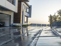 a driveway with wet floors and stairs leading to an attached garage on a high building