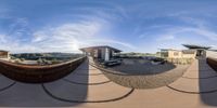 the 360 - lens is shown to see an outdoor area with benches, furniture and mountains