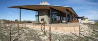 a winery building made of concrete and steel sits on a grassy hill with vines in front