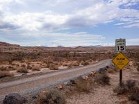 a sign in the middle of a desert road with an empty road below it, and another road below it