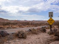 a sign in the middle of a desert road with an empty road below it, and another road below it