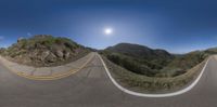 a fish eye shot of a highway going through some mountains in the distance in a 360 - camera lens