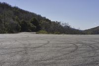 a view along a dirt road of an empty field and mountains in the distance of the scene