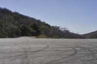 a view along a dirt road of an empty field and mountains in the distance of the scene