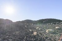 the sun is shining over a barren mountain area with a blue sky in the background