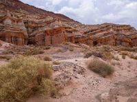 a wide view of some rock formations in the desert with grass and bushes growing out of them