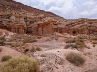 a wide view of some rock formations in the desert with grass and bushes growing out of them