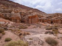 a wide view of some rock formations in the desert with grass and bushes growing out of them