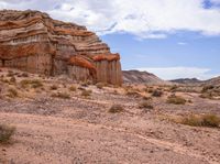 the large rock is in the middle of a desert, with sparse grass in the foreground