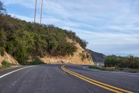 a curve road is shown with a telephone pole next to it on a cliff face