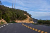 a curve road is shown with a telephone pole next to it on a cliff face