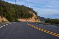 a curve road is shown with a telephone pole next to it on a cliff face