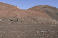 a person with a backpack stands near some large rocks and trees in the mountainside